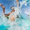Happy boy playing and splashing in swimming pool
